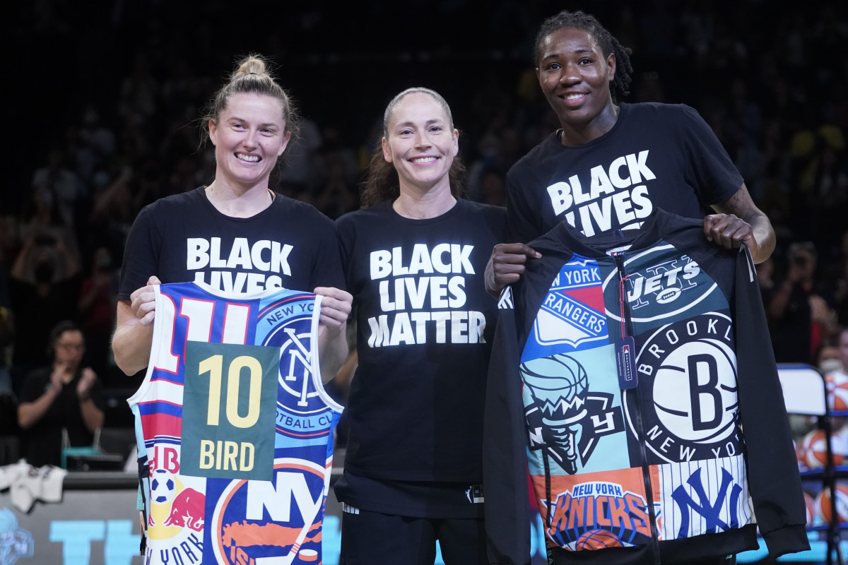 Sue Bird poses with Liberty players, who are holding gifts for the Storm star